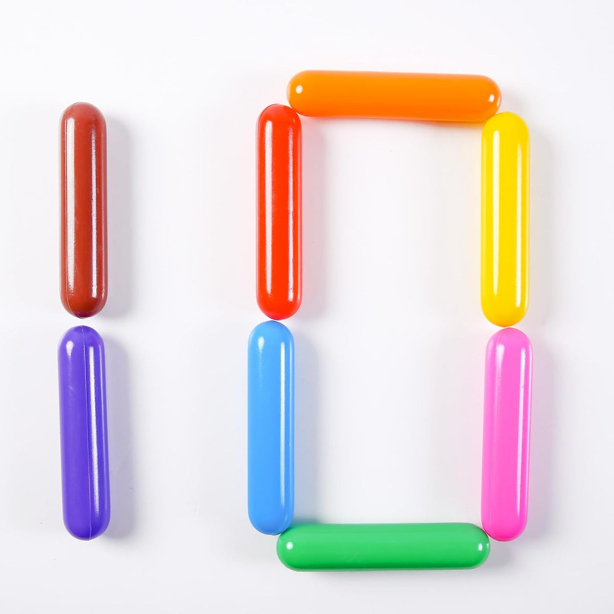 Multicolour cylinder-shaped plastic balls arranged in playful patterns on a white background.