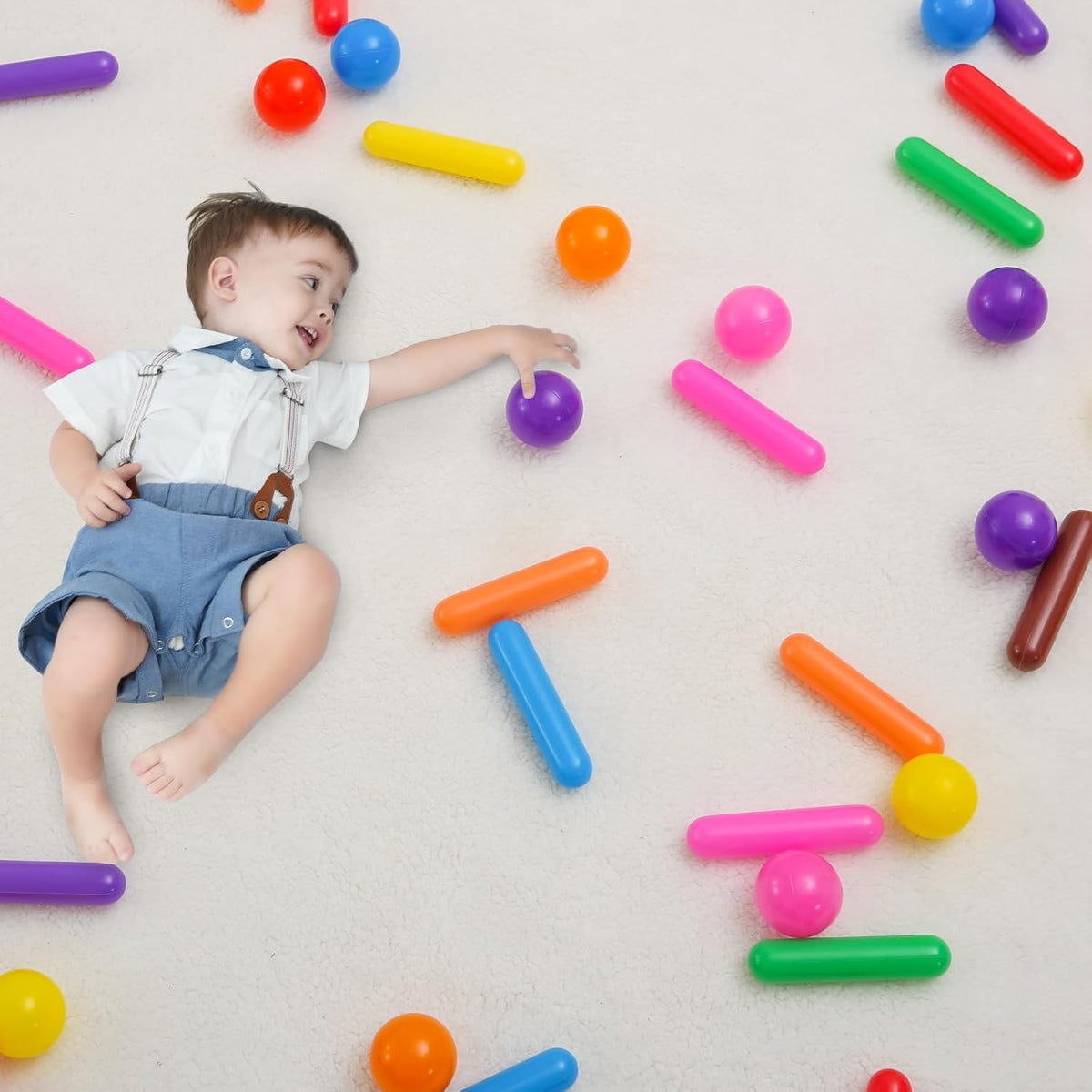 Child playing beside multicolour cylinder pieces and round ball pit balls