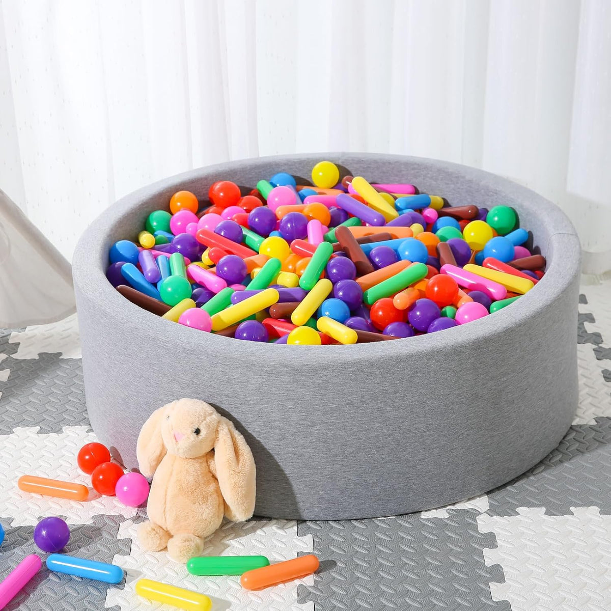 Grey ball pit filled with multicolour cylinder pieces and round balls